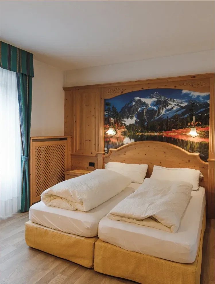 Camera con letto matrimoniale e testiera in legno decorata con paesaggio montano