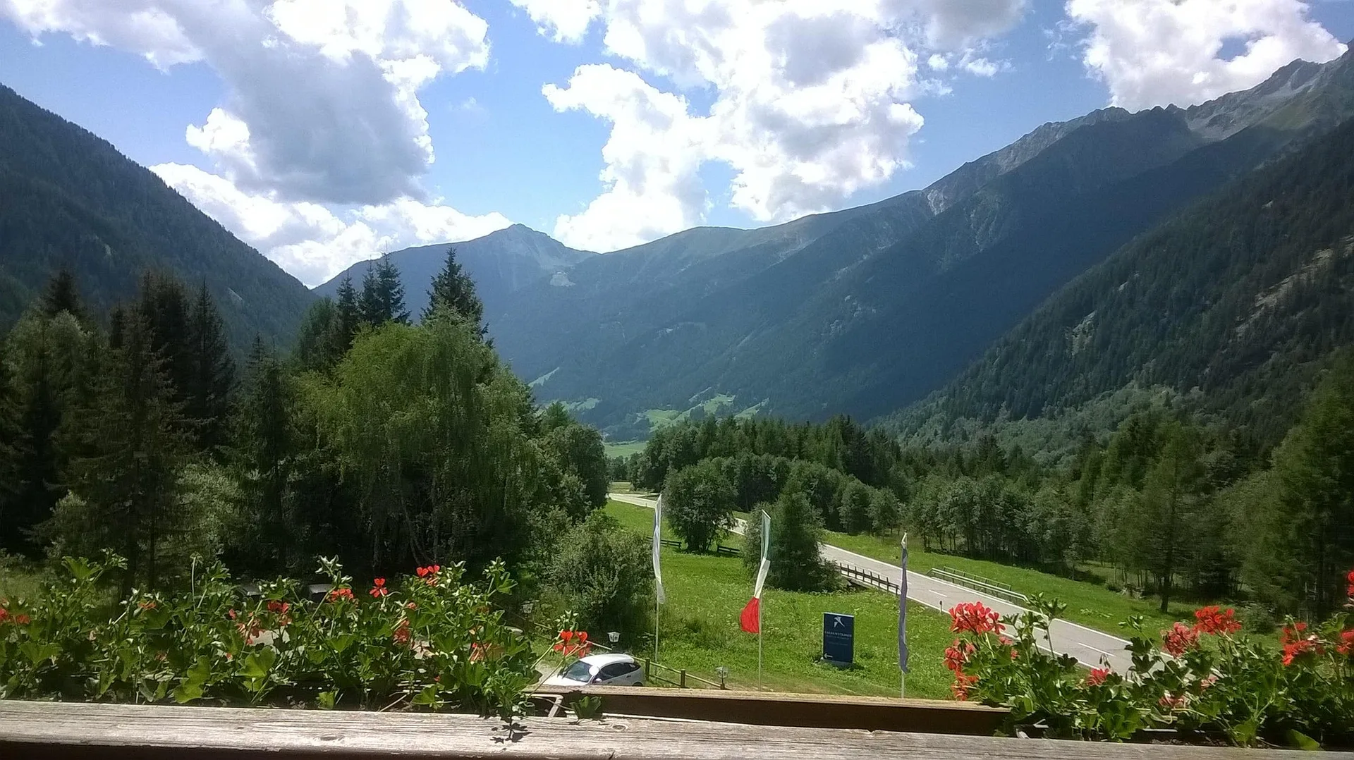 Vista panoramica sulla vallata verde e le montagne da un balcone fiorito