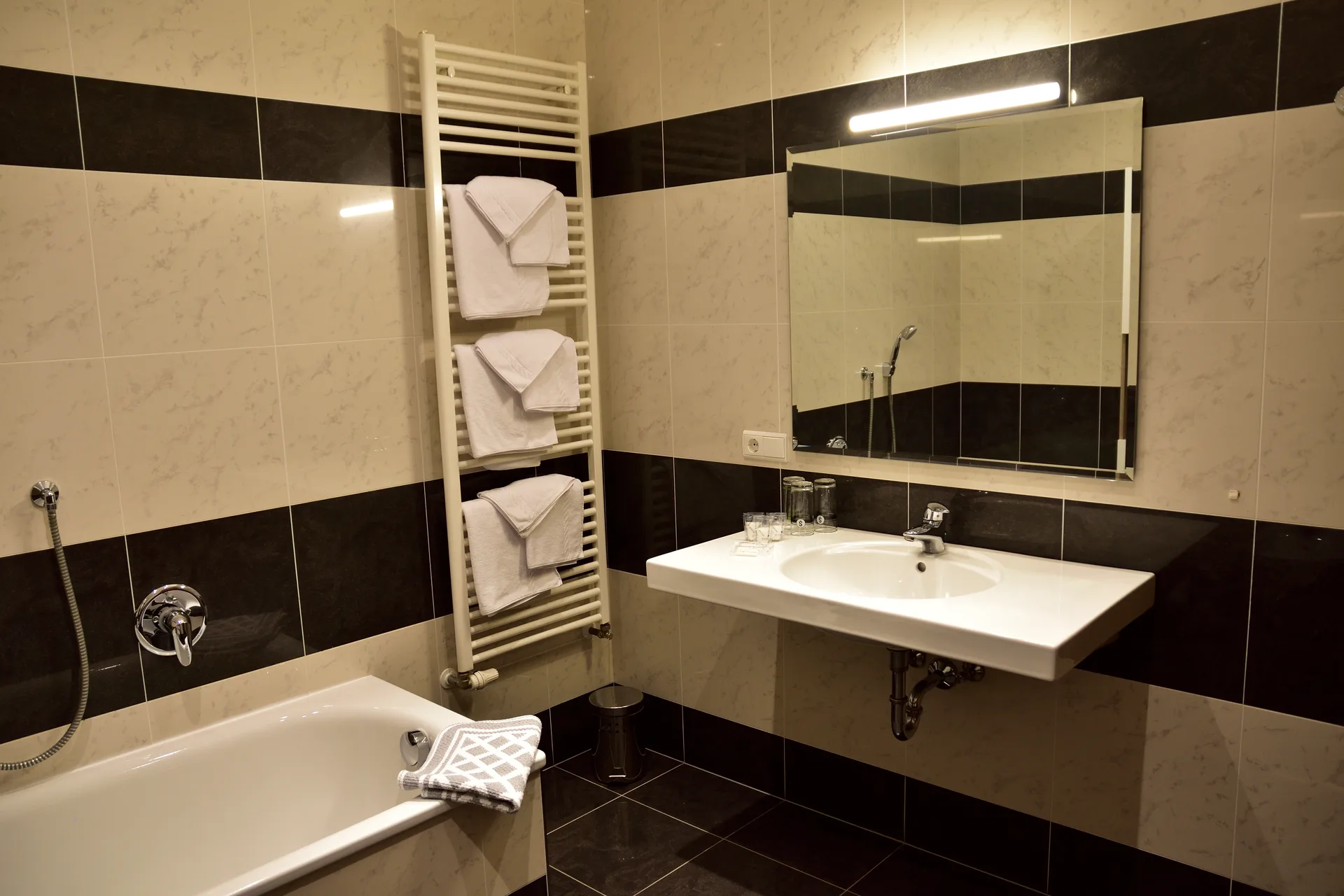 Bagno moderno con piastrelle bianche e nere, vasca, lavabo e grande specchio