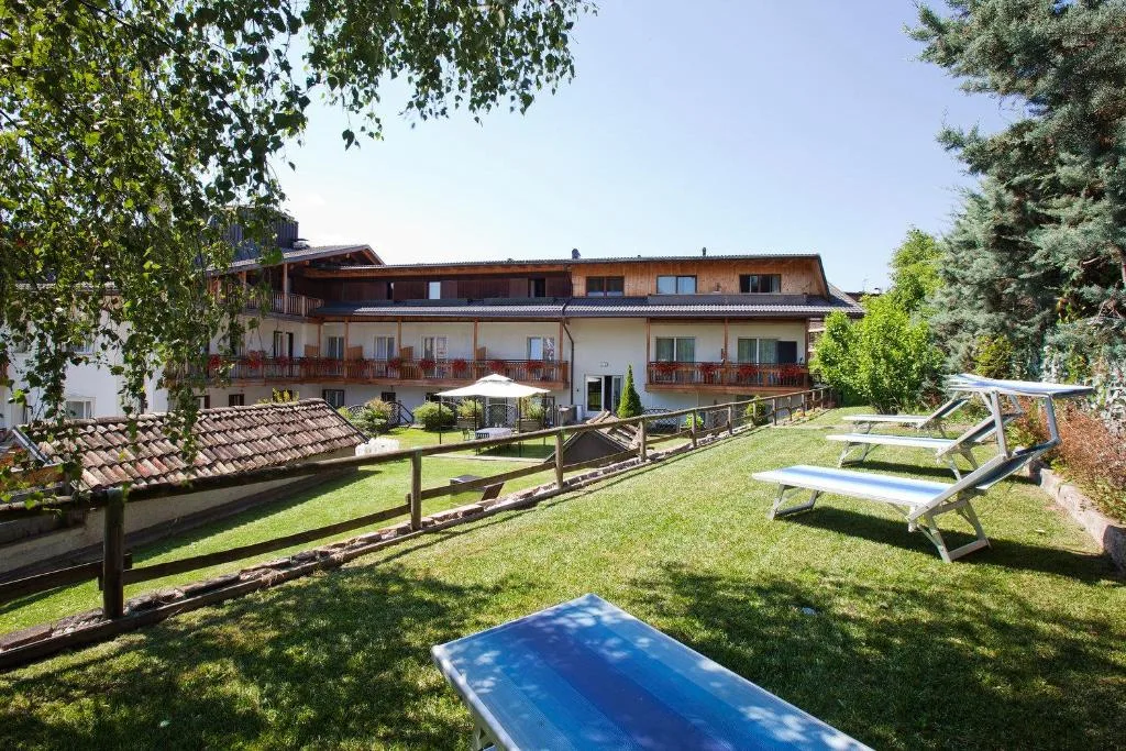 Giardino dell'hotel con prato verde, lettini e vista sull'edificio