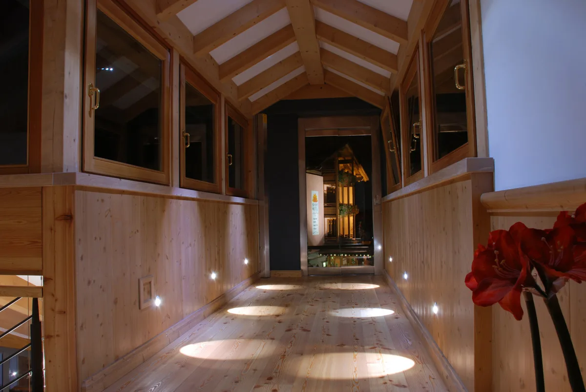 Corridoio interno con pareti e pavimento in legno chiaro e soffitto a travi