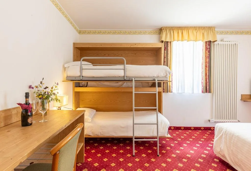 Camera con letti a castello, scrivania in legno e moquette rossa