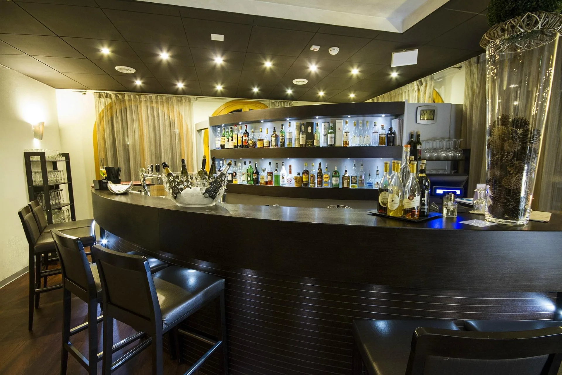 Bar dell'hotel con bancone in legno scuro e ampia selezione di bottiglie