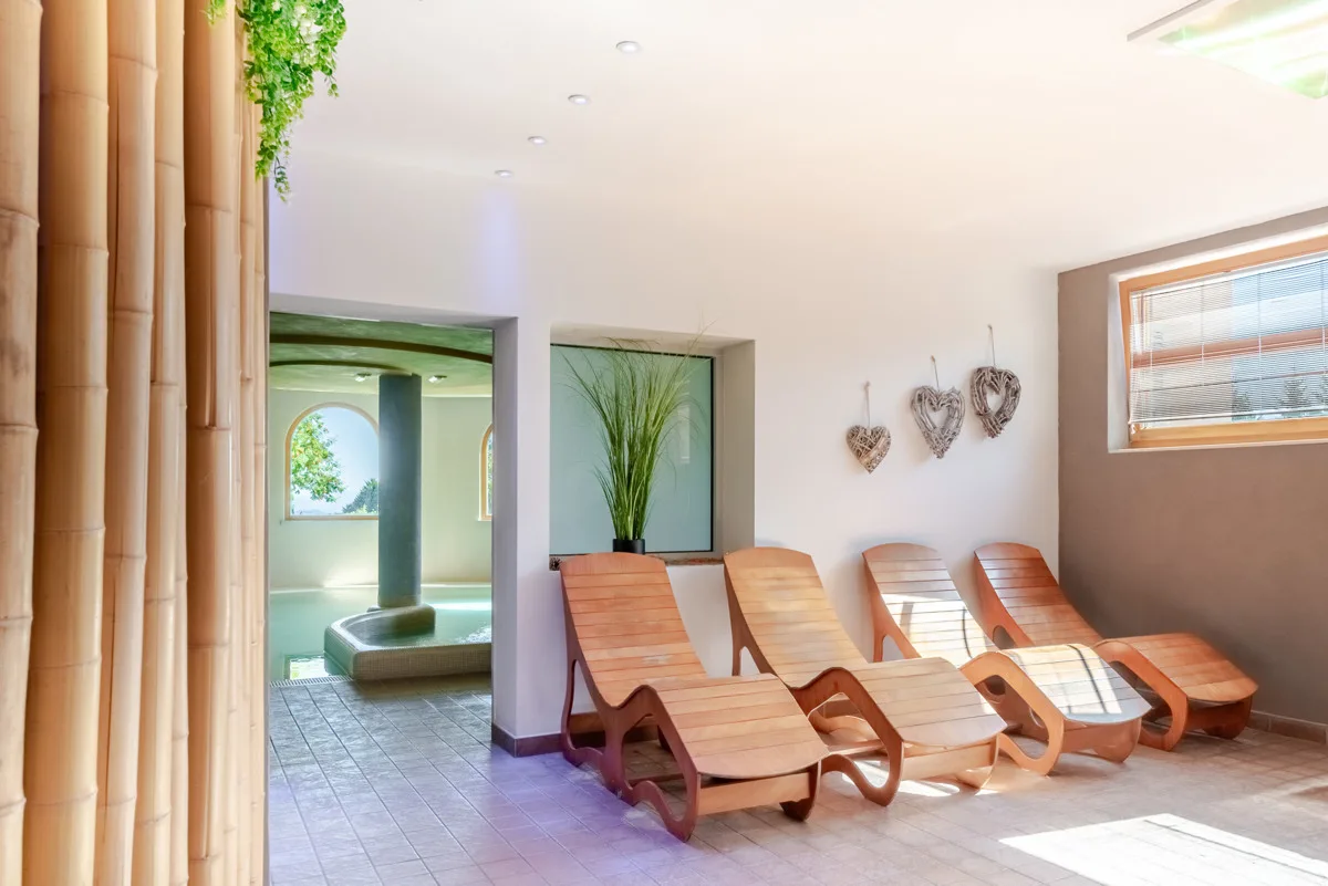 Area relax della spa con lettini in legno e piscina interna