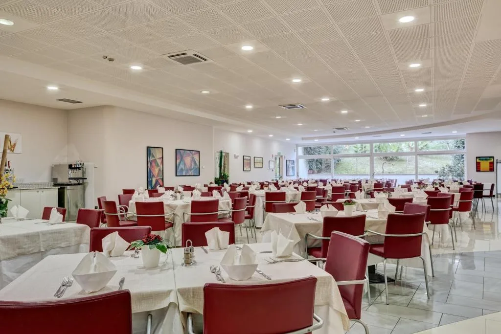Sala ristorante interna con tavoli apparecchiati e sedie rosse