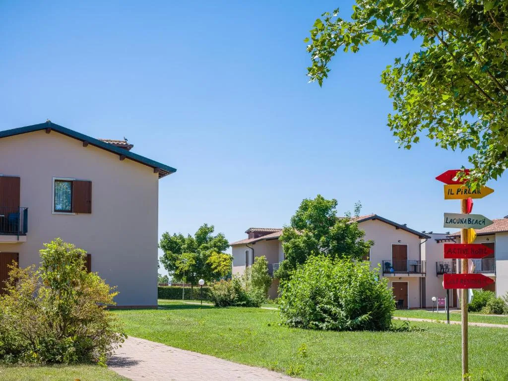Vialetto tra edifici residenziali con cartelli segnaletici e vegetazione