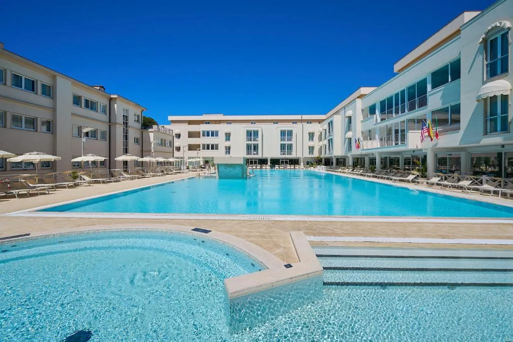 Piscina panoramica dell'hotel con vasca idromassaggio, ombrelloni e bandiere internazionali