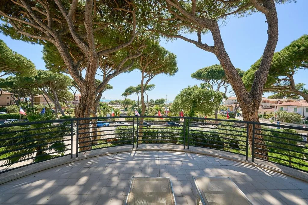Terrazza panoramica con lettini affacciata su pini marittimi e giardino
