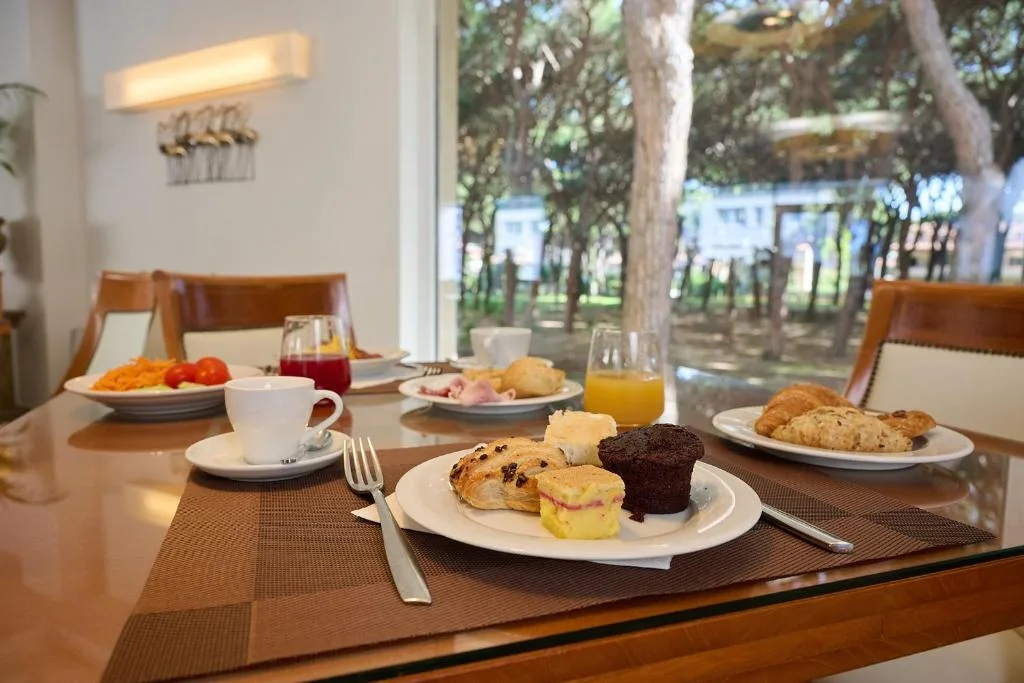 Tavolo apparecchiato per la colazione con dolci, caffè e succhi affacciato sul verde