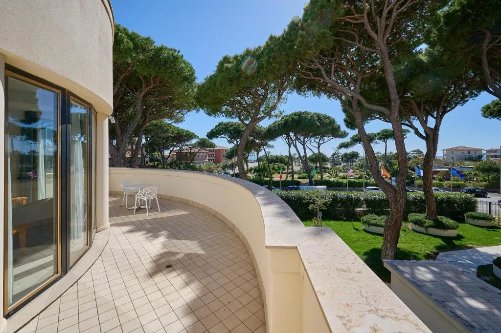 Ampia terrazza curva con tavolino e vista sui pini marittimi e il giardino