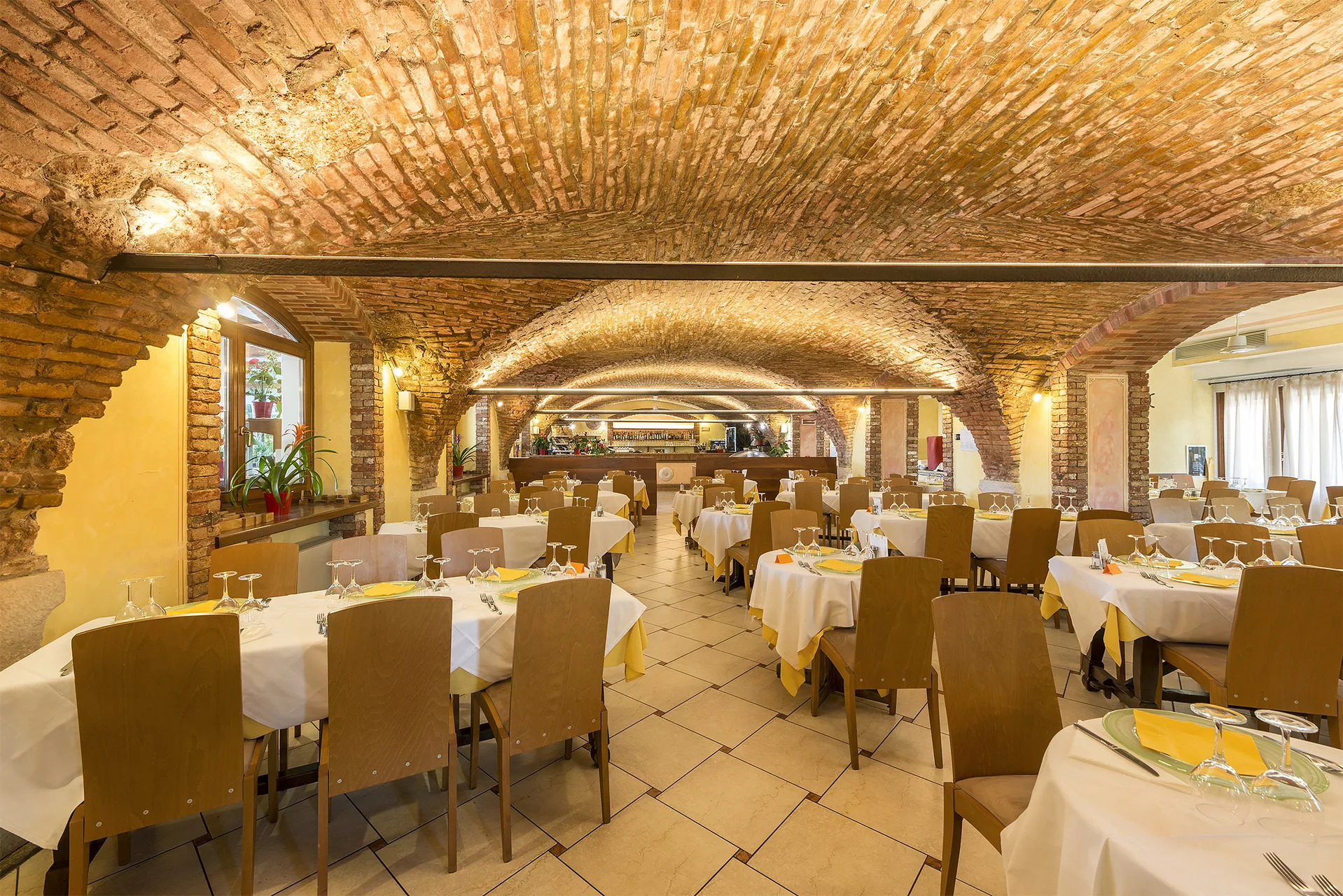 Sala ristorante interna con volte in mattoni a vista e tavoli apparecchiati