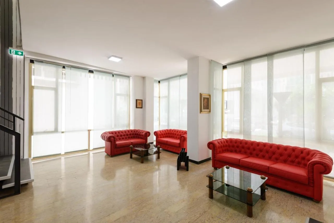 Sala soggiorno luminosa con divani in pelle rossa e ampie vetrate