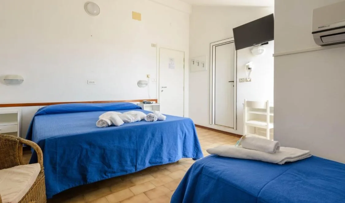Camera con letto matrimoniale e singolo, copriletto blu, TV e aria condizionata