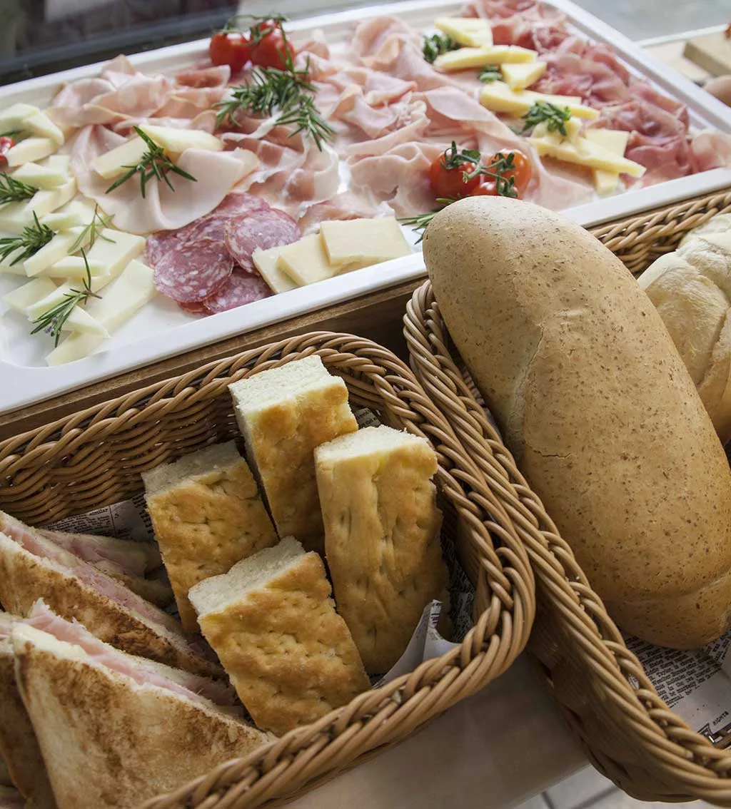 Vassoio di salumi e formaggi con cestini di pane e focaccia per la colazione