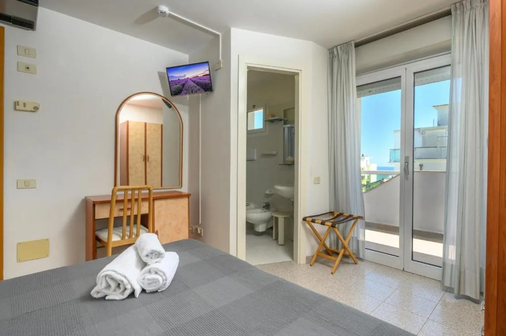 Camera con TV, specchio, scrivania, bagno privato e balcone con vista mare
