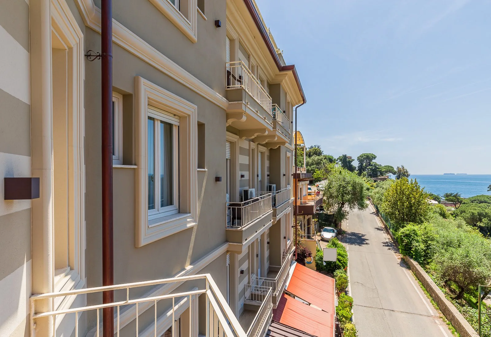 Vista laterale della facciata dell'hotel con balconi e scorcio sul mare e la strada costiera