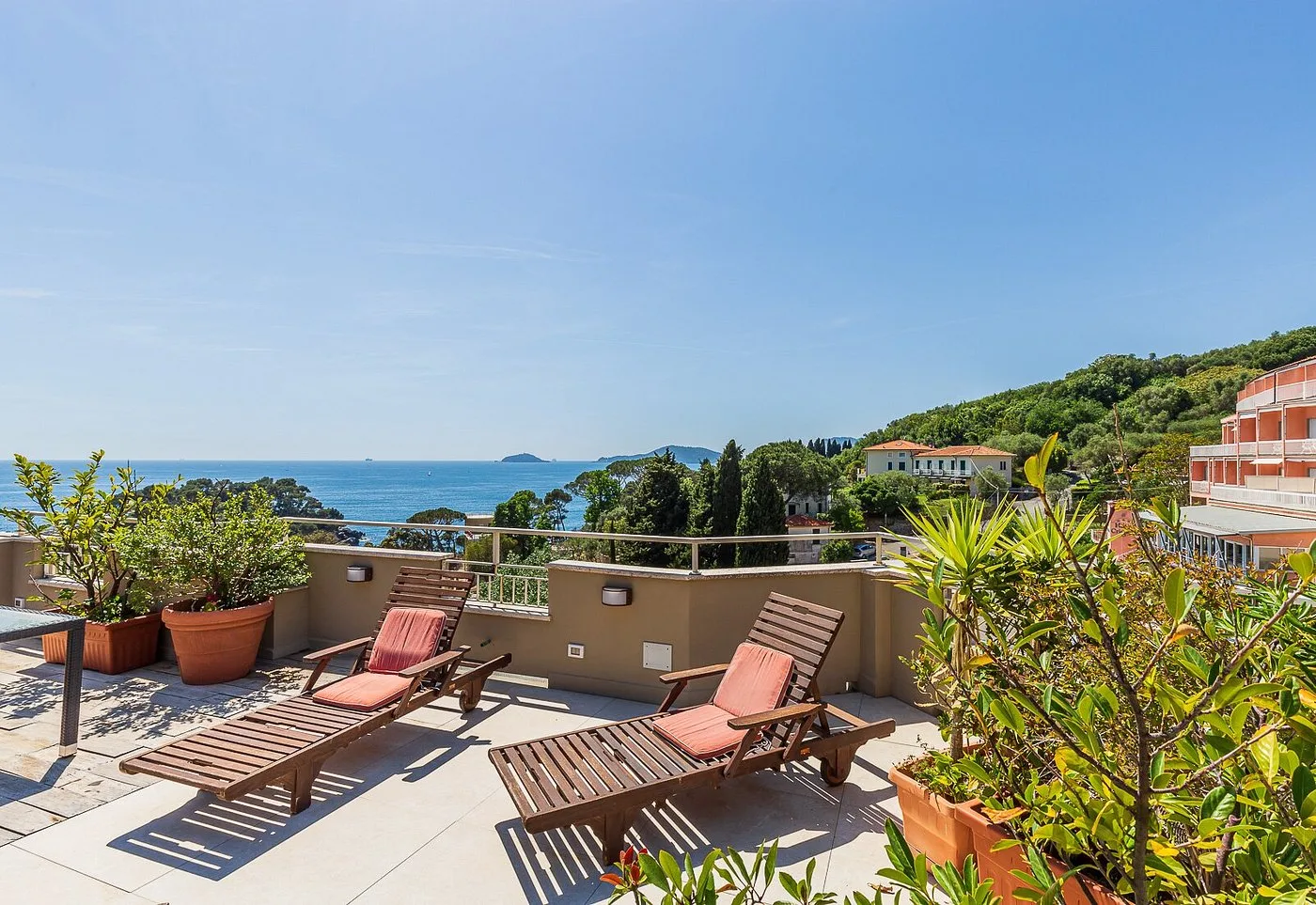 Terrazza solarium con lettini in legno e piante affacciata sul golfo e le isole