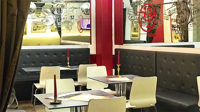Sala interna con tavoli, sedie bianche, divani in pelle e candele rosse