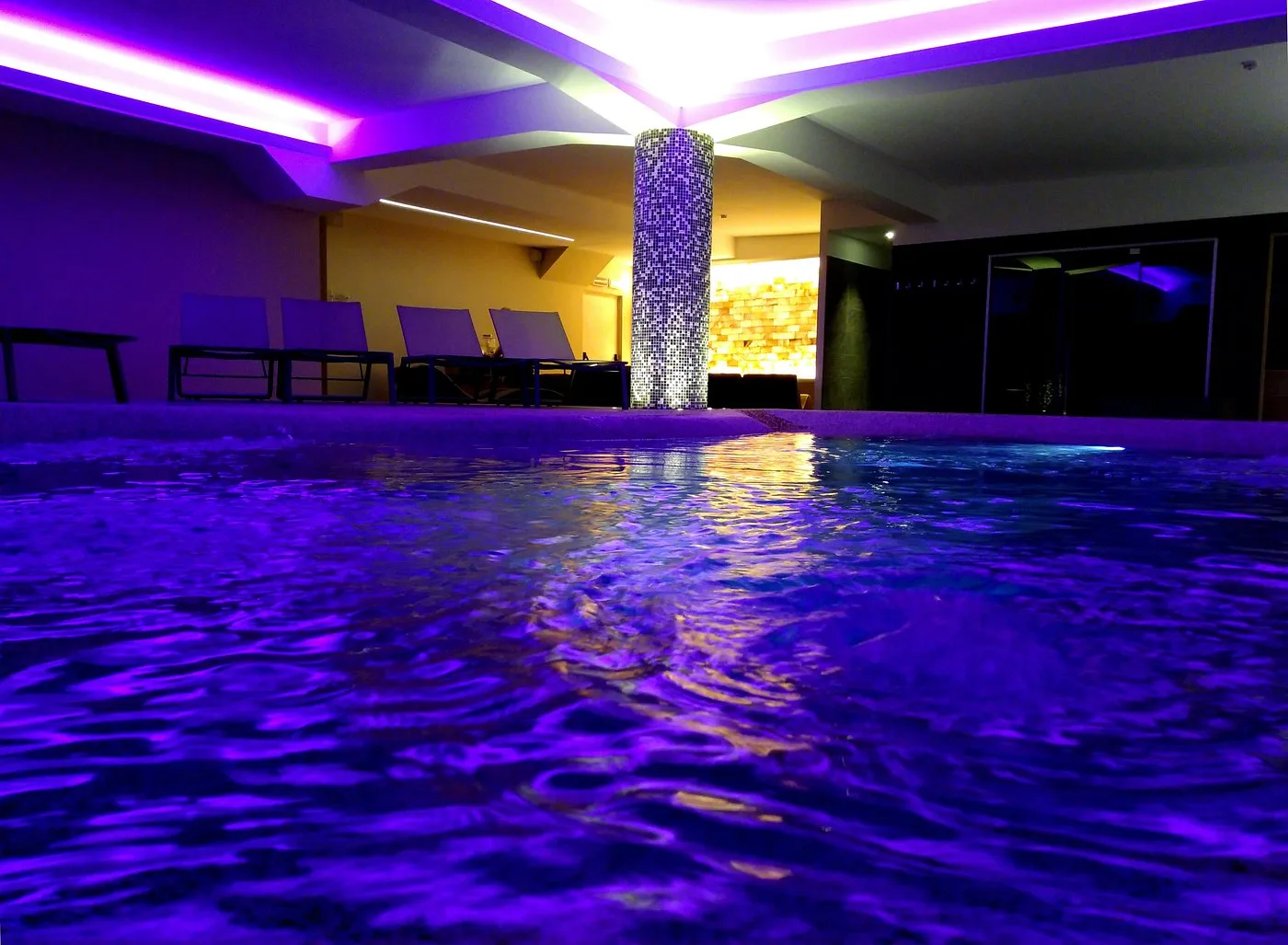 Piscina interna illuminata con luci viola e riflessi sull'acqua