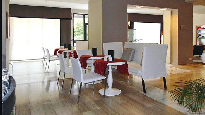 Sala colazione con tavolini bianchi e sedie eleganti