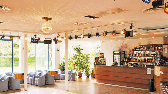 Hall con bancone bar, poltrone e faretti colorati con sfera specchiata
