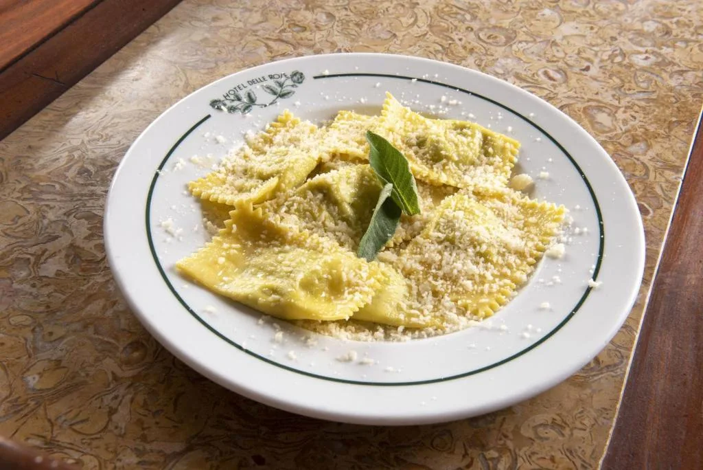 Piatto di ravioli con parmigiano e salvia servito su tavolo in marmo