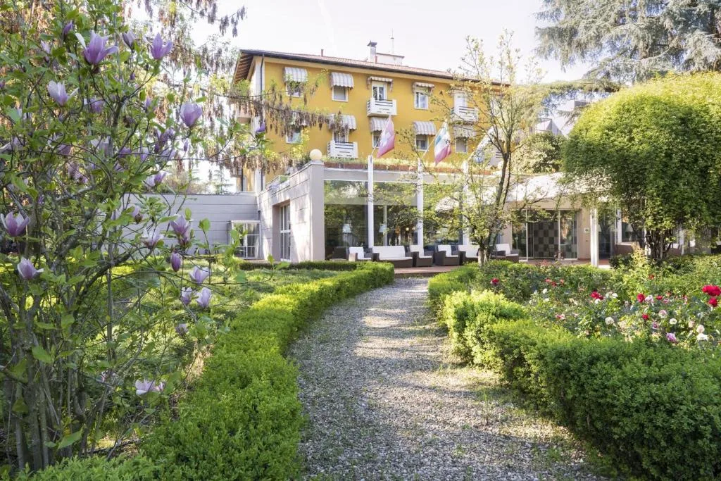 Vialetto in ghiaia nel giardino curato con magnolie in fiore verso l'ingresso dell'hotel giallo