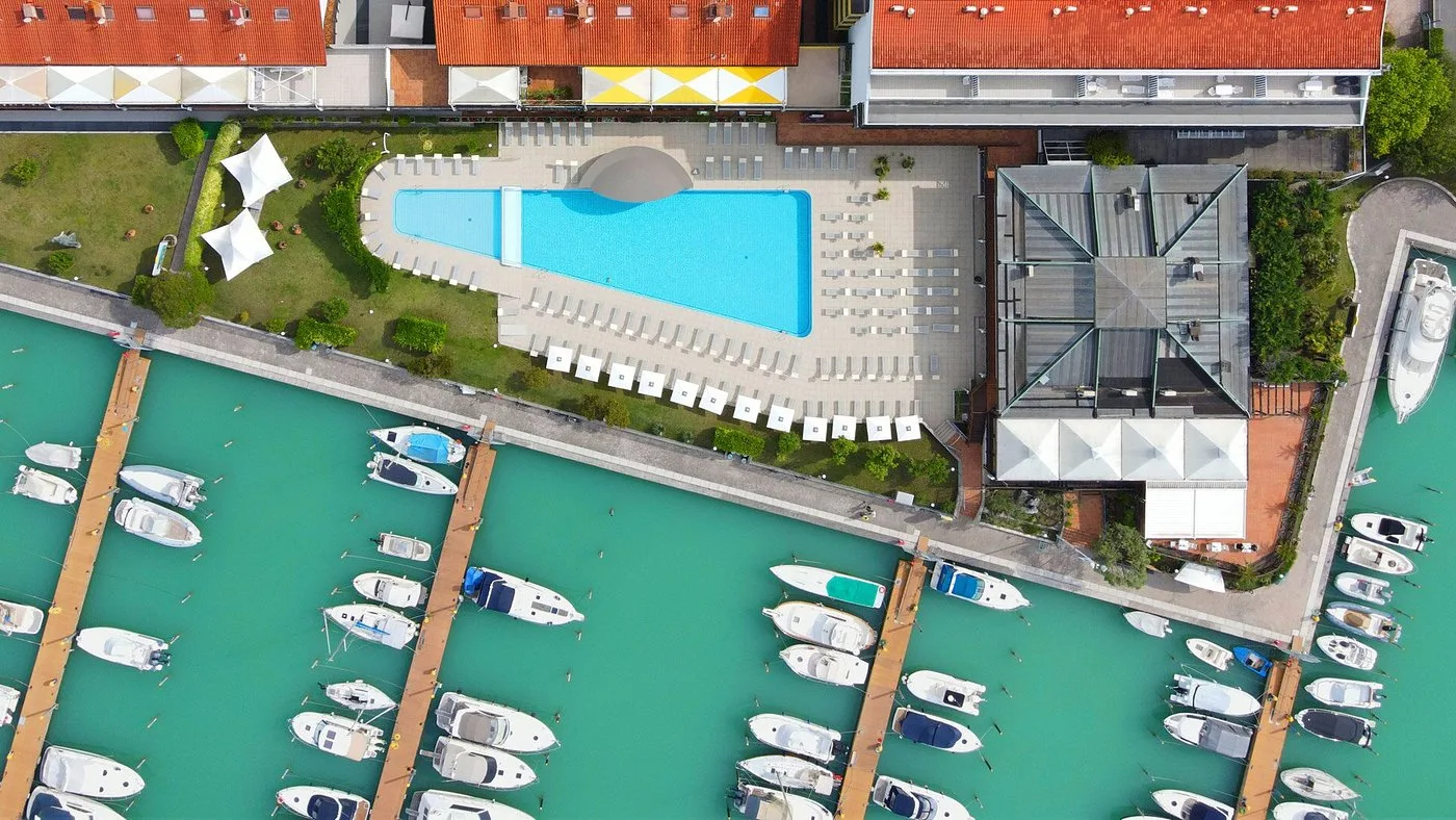 Vista aerea della piscina dell'hotel accanto alla marina con barche