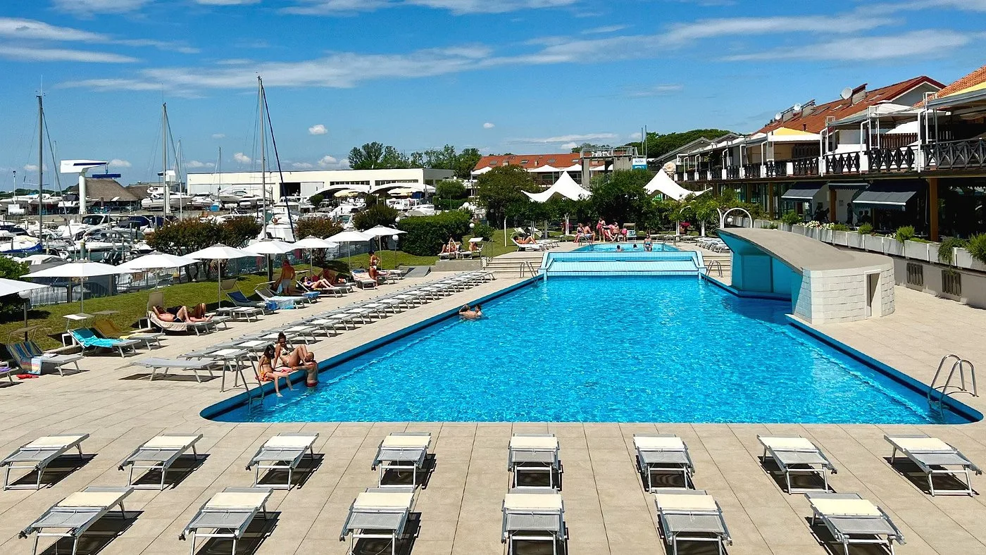 Ampia piscina esterna con lettini e vista sul porto turistico