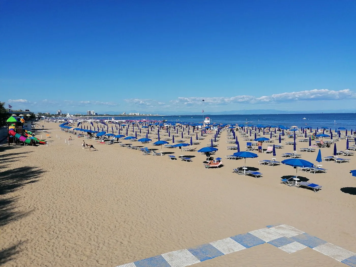 Spiaggia sabbiosa con ombrelloni blu e mare limpido