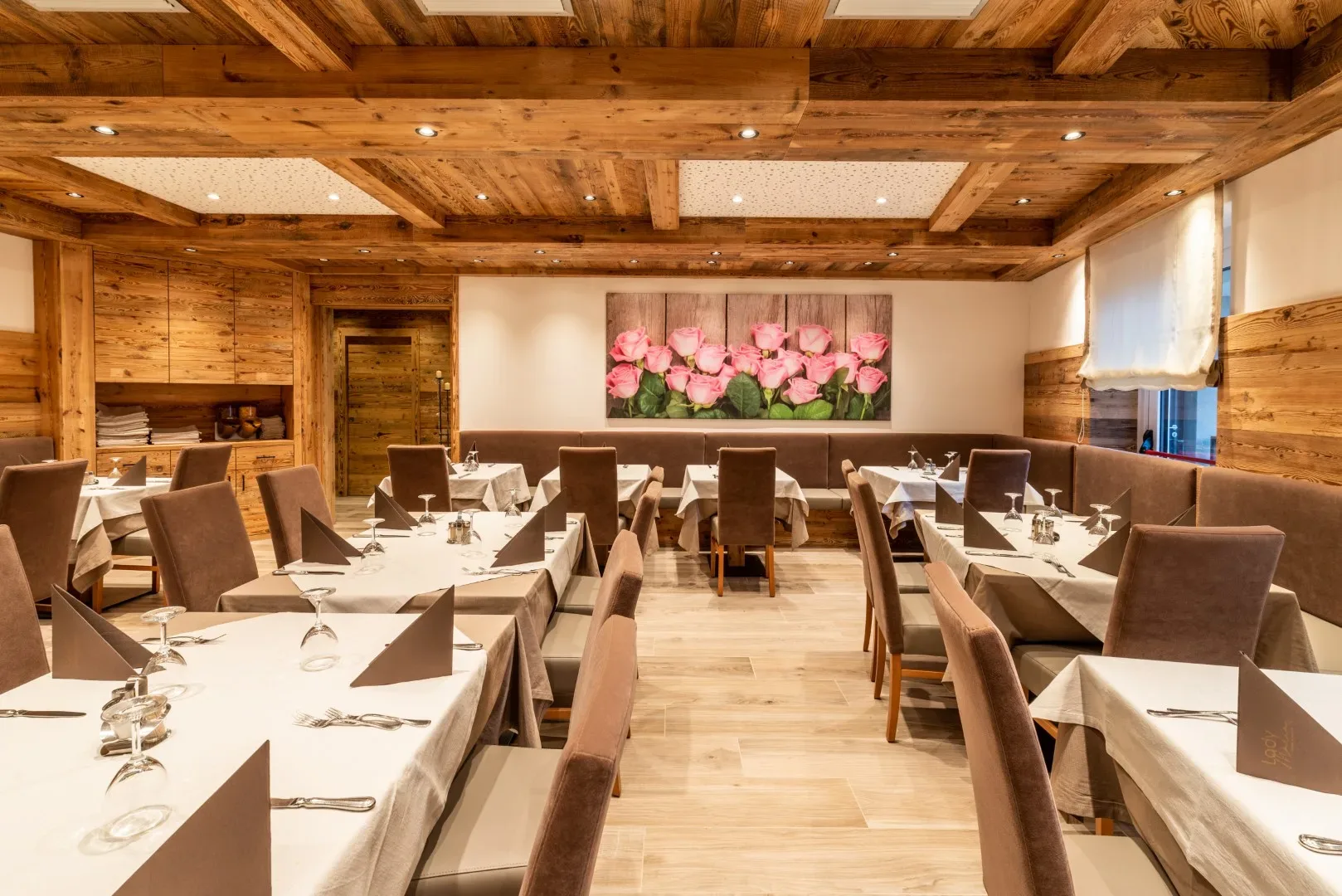 Sala ristorante elegante con tavoli apparecchiati e quadro di rose rosa