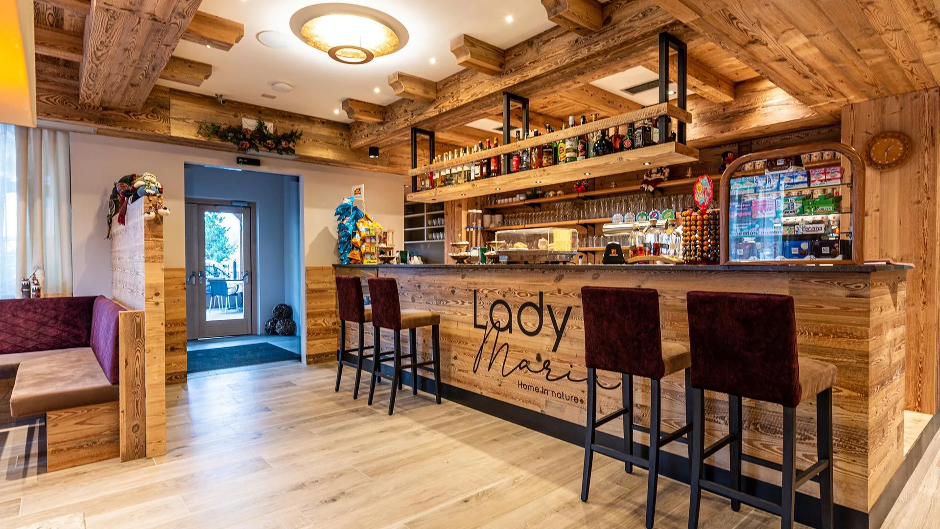 Bar dell'hotel in legno con sgabelli e bottiglie in stile alpino