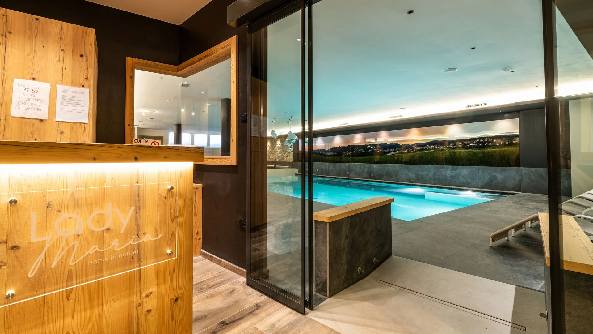 Ingresso della zona benessere con piscina interna illuminata e panorama panoramico