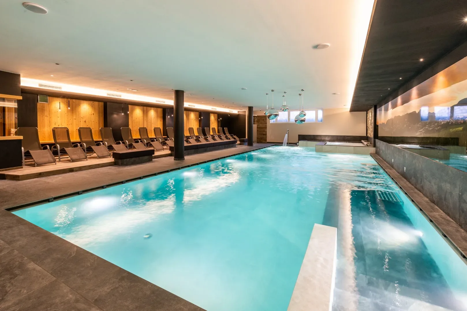 Piscina interna riscaldata con lettini, idromassaggio e murale panoramico