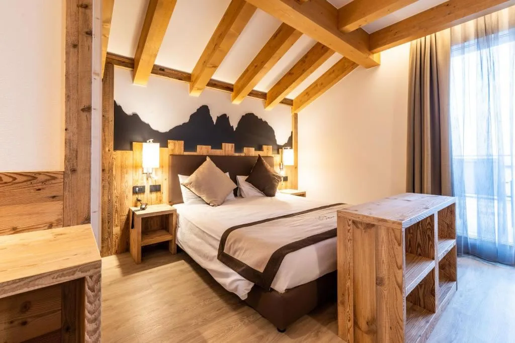 Camera matrimoniale in stile alpino con testiera decorata e travi in legno a vista