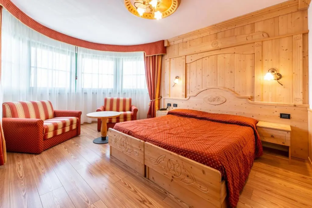 Camera classica in legno con letto matrimoniale, divano e ampie finestre