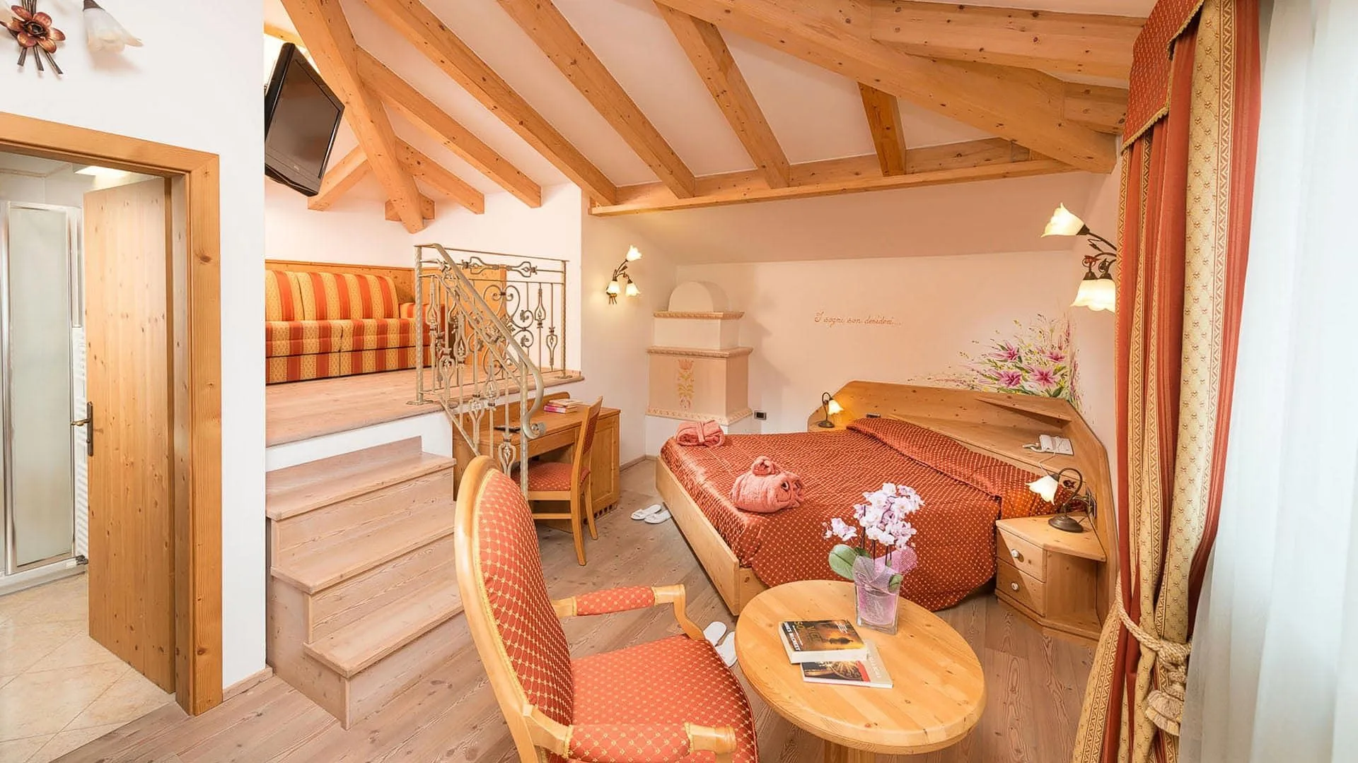 Suite mansardata con letto, stufa in maiolica e zona lounge soppalcata