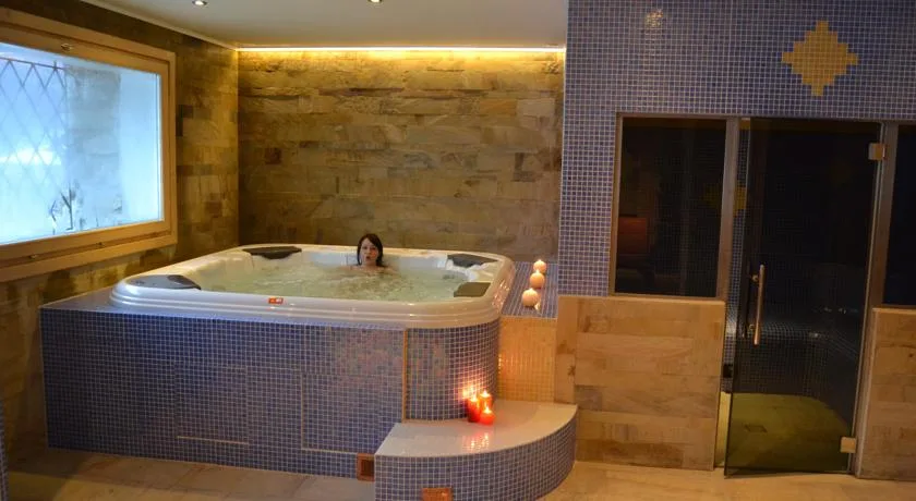 Vasca idromassaggio della spa con mosaico blu e candele accese