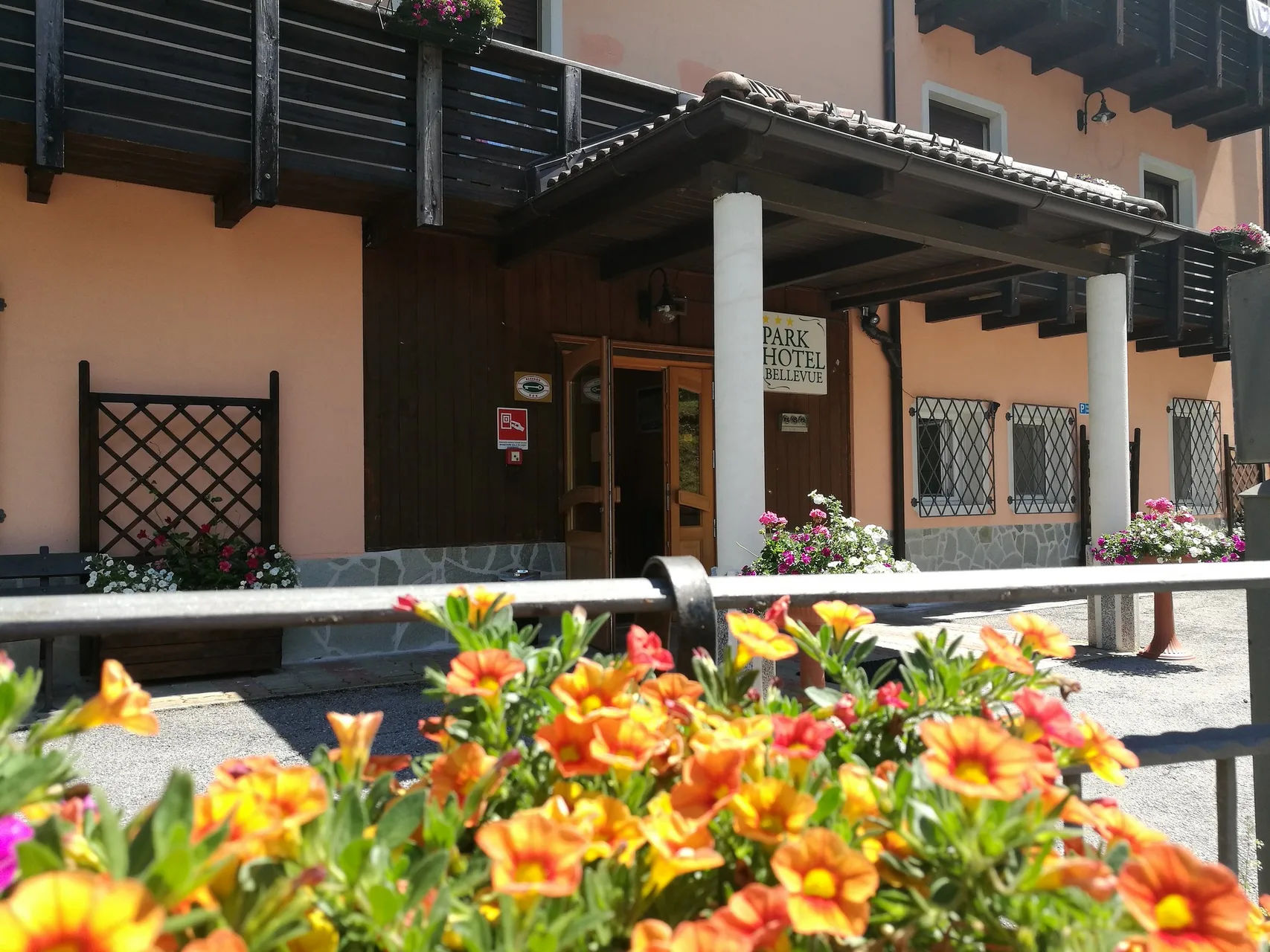Ingresso del Park Hotel Bellevue con portico in legno e fiori colorati in estate