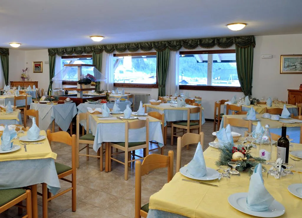 Sala ristorante dell'hotel con tavoli apparecchiati e vista sulle montagne dalle finestre