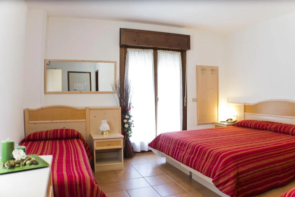 Camera dell'hotel con letto matrimoniale e letto singolo, copriletto a righe rosse