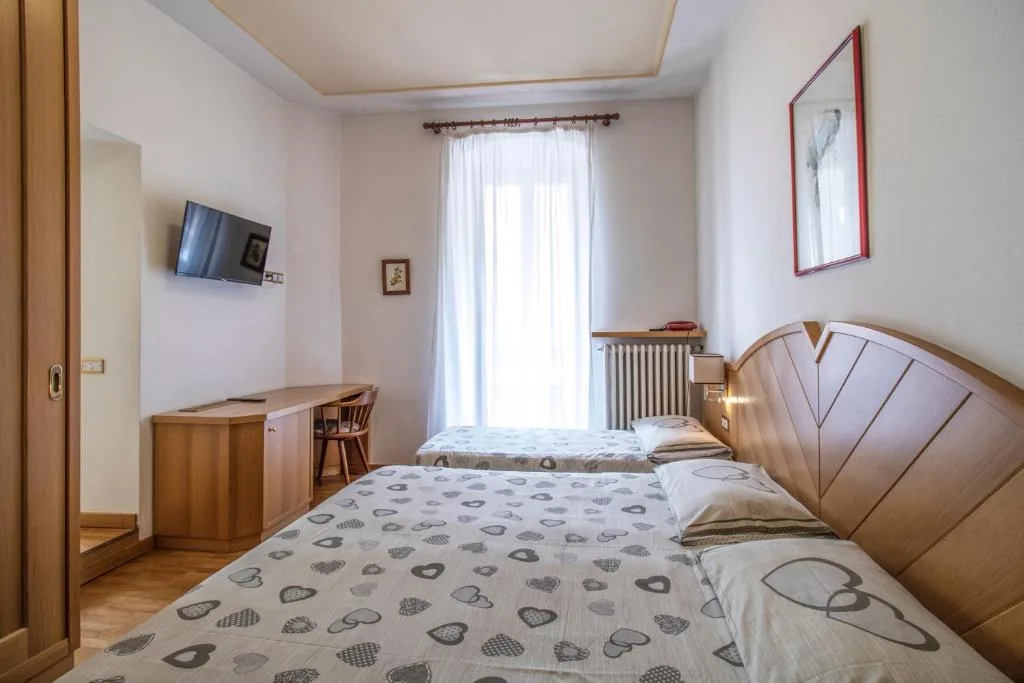 Camera con letto matrimoniale e letto singolo, TV a parete e arredi in legno
