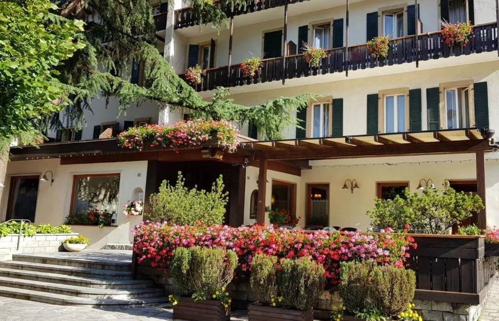 Ingresso dell'hotel con portico in legno, fiori colorati e piante
