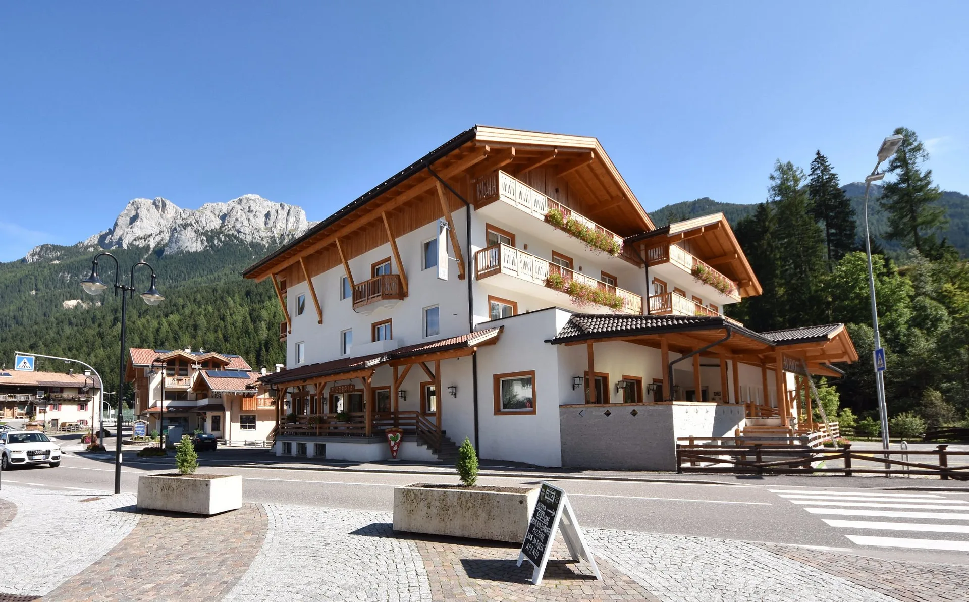 Facciata dell'hotel in estate con montagne verdi e cielo azzurro