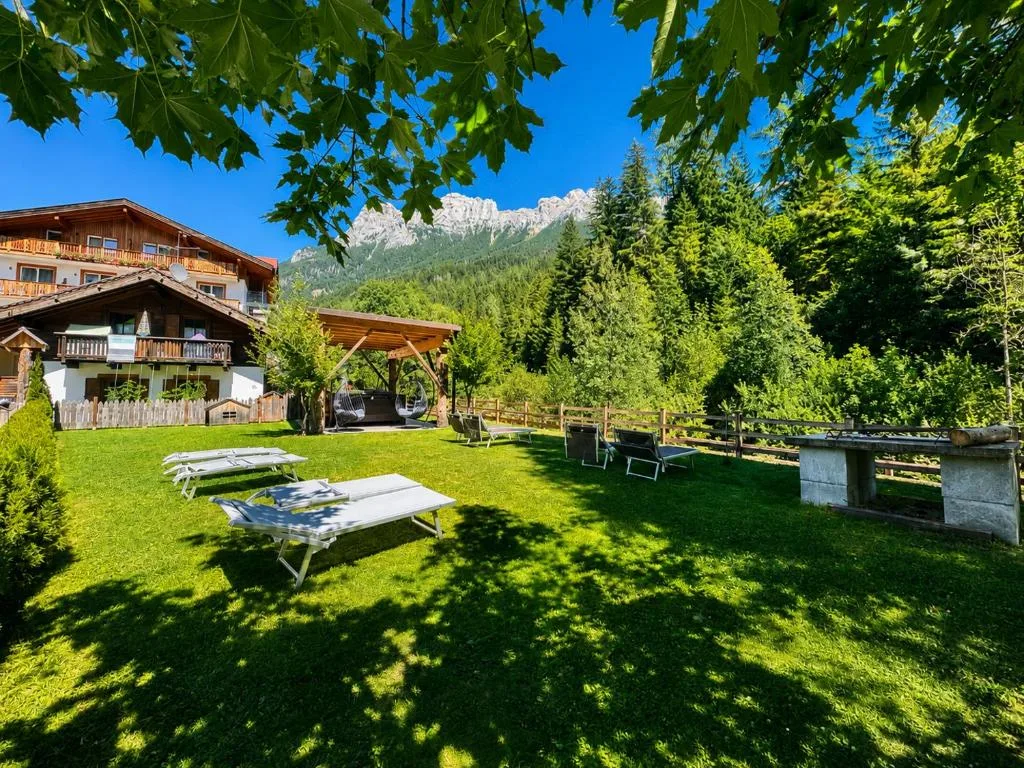 Giardino estivo dell'hotel con lettini prendisole sul prato e vista sulle Dolomiti