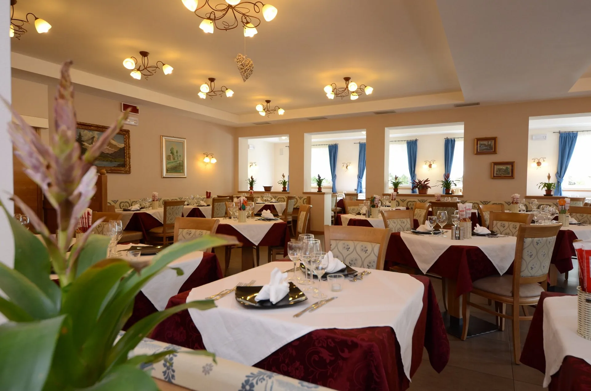 Dettaglio della sala ristorante con tavoli eleganti e pianta in primo piano