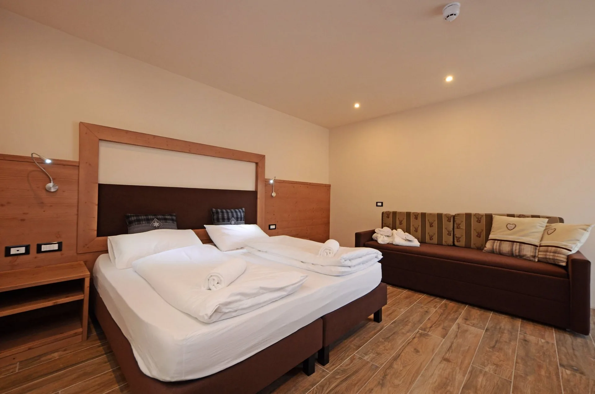 Camera moderna con letto matrimoniale, divano e testata in legno