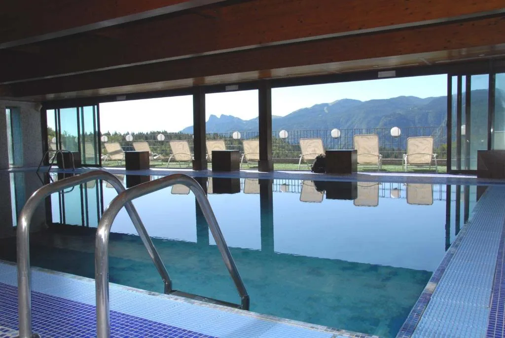 Piscina interna con ampie vetrate e vista panoramica sulle montagne