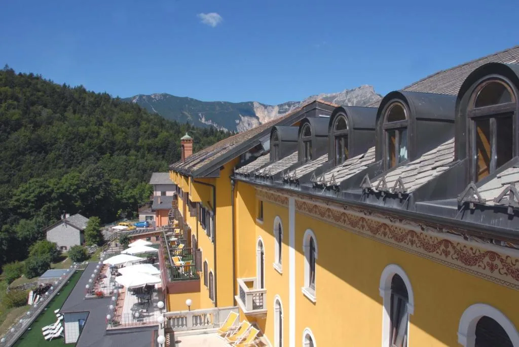 Vista laterale dell'hotel giallo con terrazza e montagne sullo sfondo