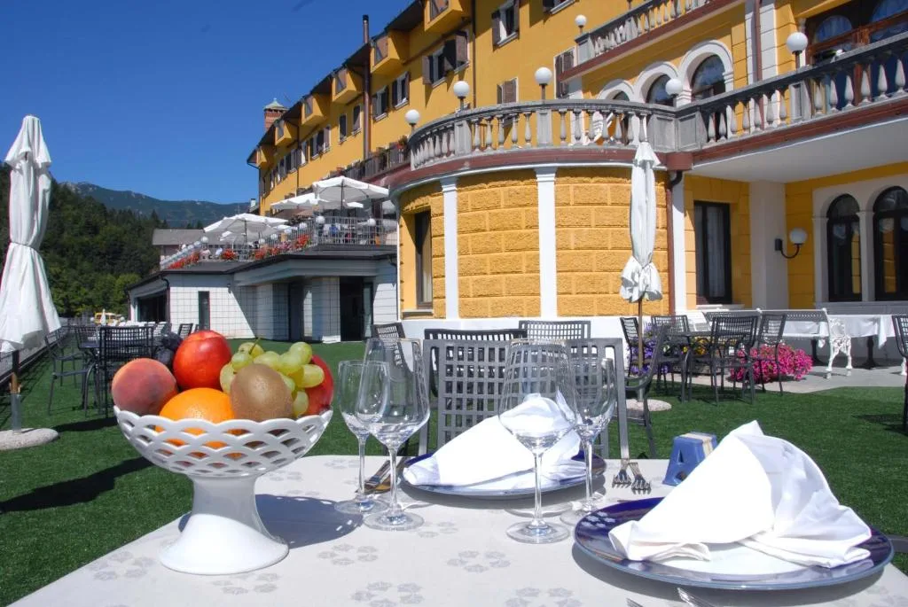 Tavolo apparecchiato sulla terrazza con cesto di frutta e vista sull'hotel